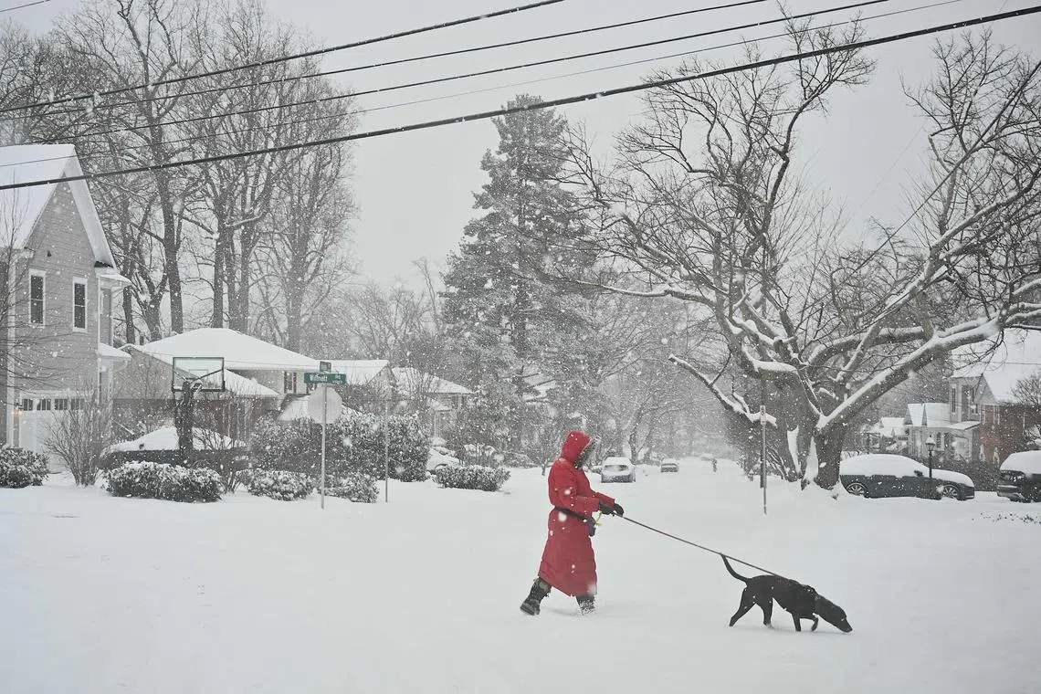 A pedestrian crosses the street as snow falls during a winter storm in Bethesda, Maryland on Jan 6.