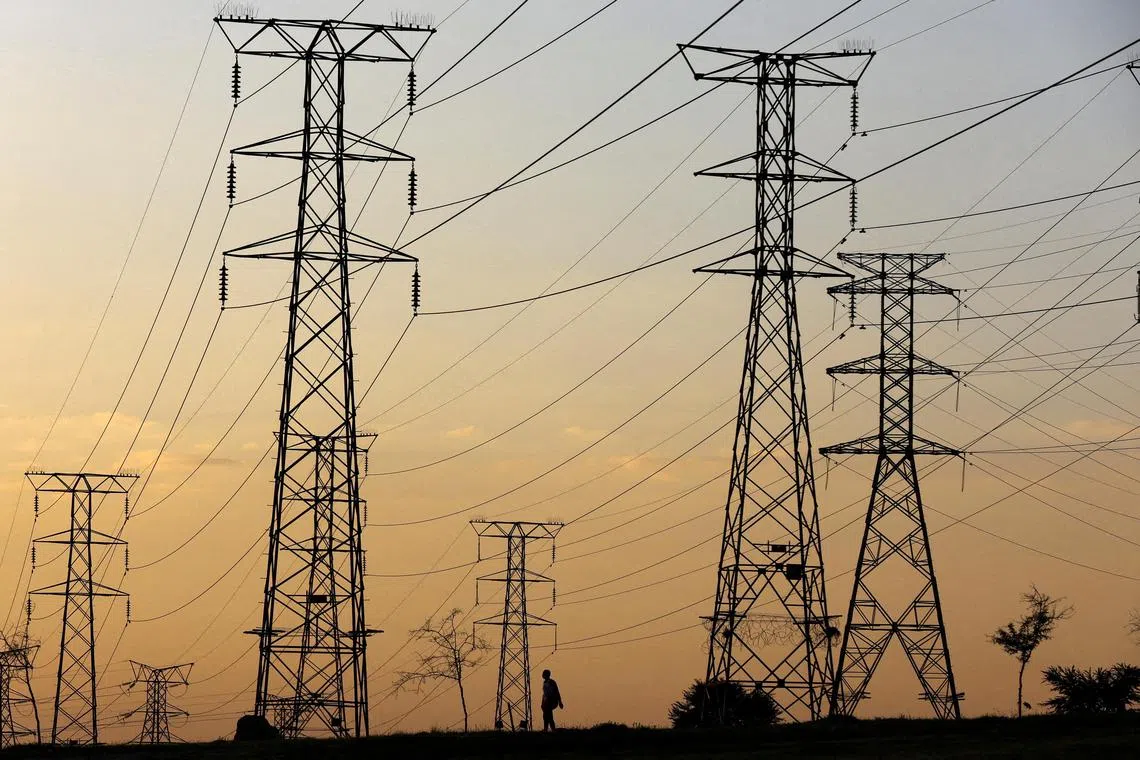 FILE PHOTO: A man walks beneath electricity pylons during frequent power outages from South African utility Eskom, caused by its ageing coal-fired plants, in Orlando, Soweto, South Africa, January 16, 2023. REUTERS/Siphiwe Sibeko/File Photo