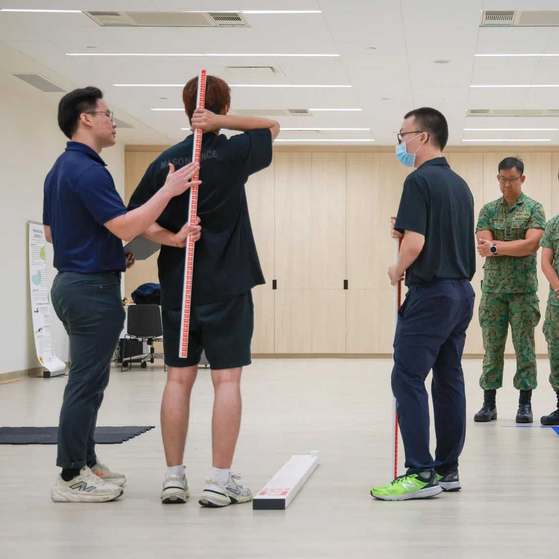 Minister for Defence Chan Chun Sing (third from right) observing a pre-enlistee undergoing a medical assessment at the regional health hub on April 13.