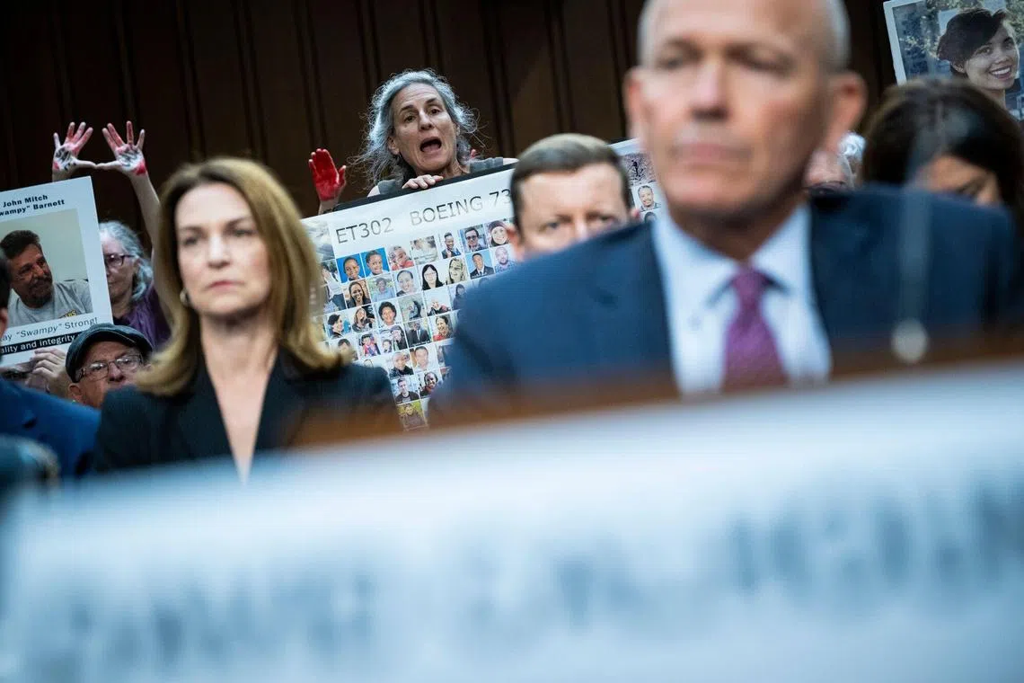 A demonstrator shouts at Boeing CEO Dave Calhoun prior to a Senate hearing in Washington.