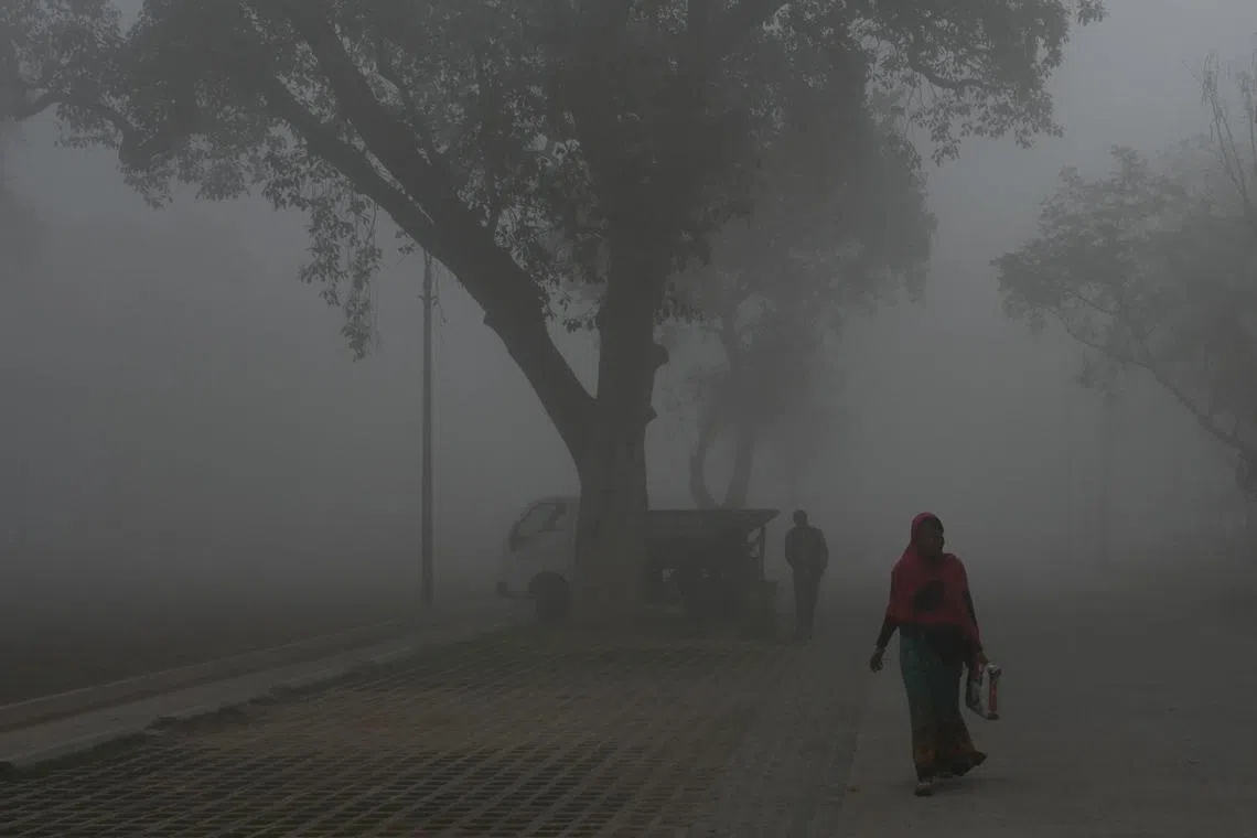 People walk along a road near India Gate amid heavy smog in New Delhi on February 22, 2023. (Photo by Arun SANKAR / AFP)