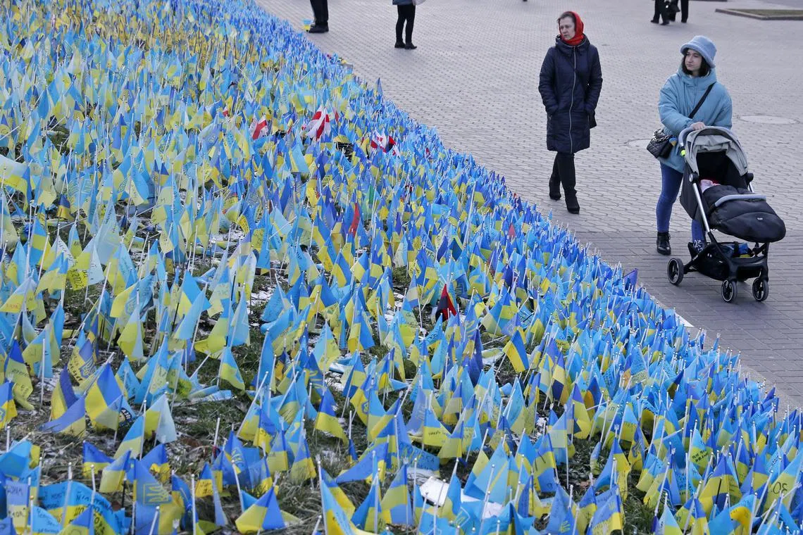 People walk past Ukrainian flags which are placed on Independence Square in commemoration of fallen Ukrainian soldiers, in Kyiv, Ukraine on Feb 22, 2023. Russian troops on 24 February entered Ukrainian territory, starting a conflict that has provoked destruction and a humanitarian crisis. 