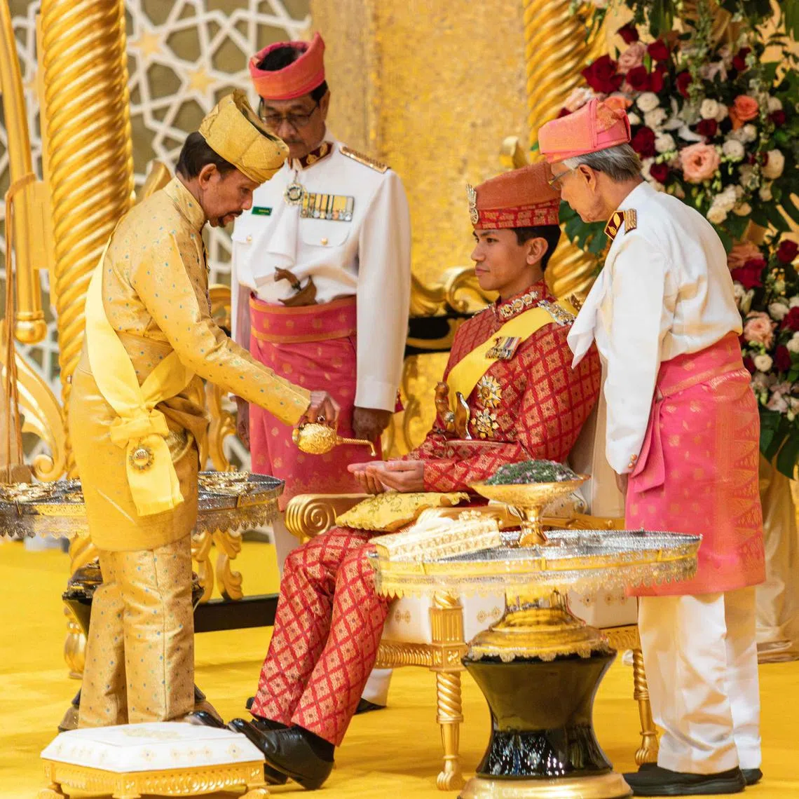 This photograph taken on January 10, 2024 shows Brunei's Sultan Hassanal Bolkiah (2nd L) pouring scented oil on the hands of Prince Abdul Mateen during the royal powdering ceremony at Istana Nurul Iman, ahead of his wedding to Anisha Rosnah, in Bandar Seri Begawan, as Queen Raja Isteri Pengiran Anak Hajah Saleha (L) looks on. 