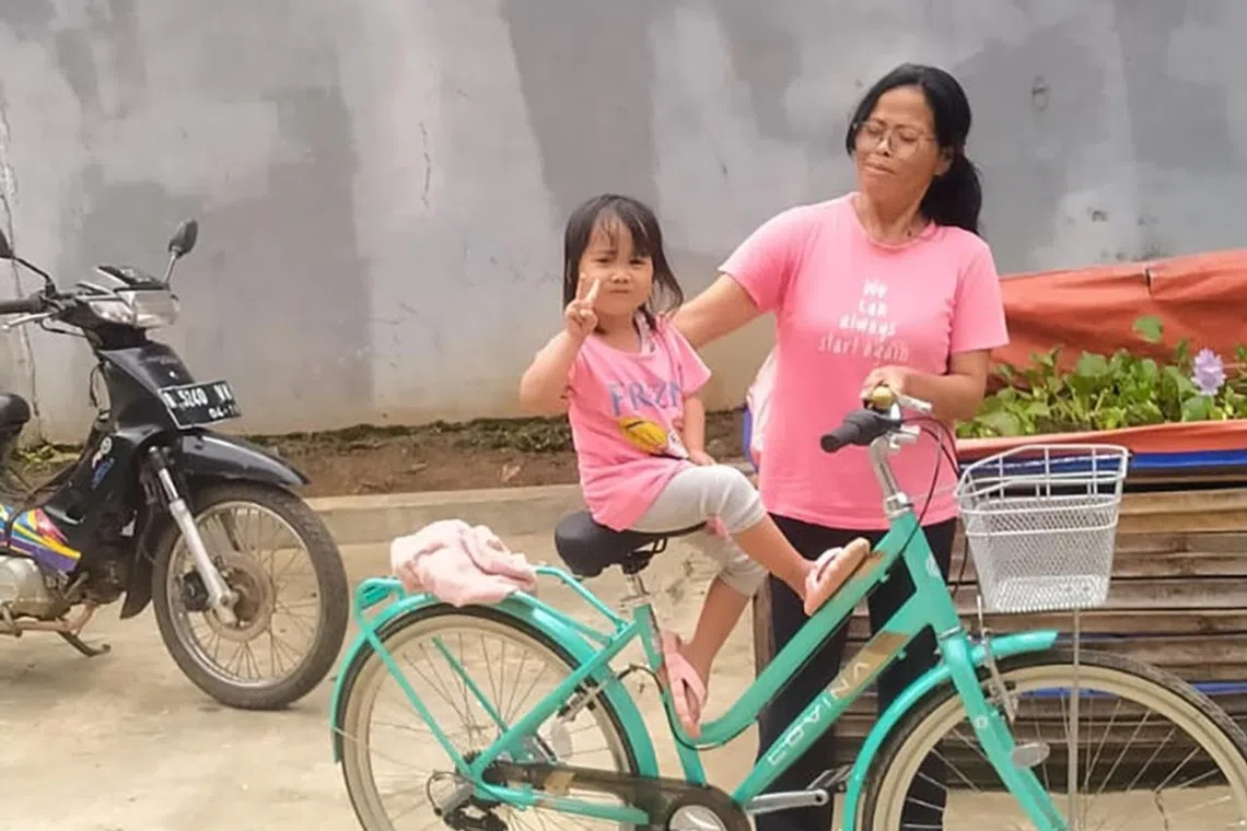 Ms Darwati with her four-year-old granddaughter posing in matching pink T-shirts outside their house in Majenang district, Cilacap regency, Indonesia.