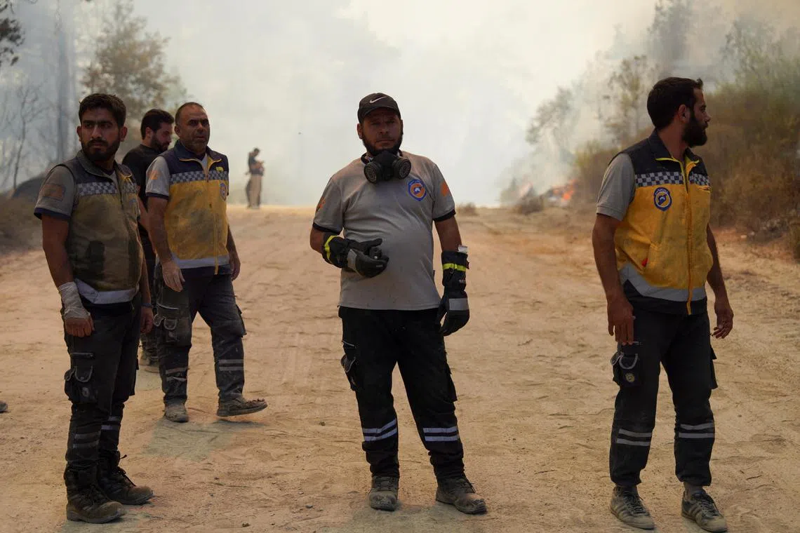 Members of the Syrian Civil Defence, also known as the White Helmets, working to extinguish a wildfire in Syria's Latakia province on July 6.