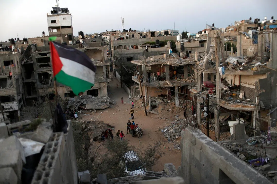 FILE PHOTO: A Palestinian flag flies as the ruins of houses, which were destroyed by Israeli air strikes during the Israeli-Palestinian fighting, are seen, in Gaza Strip, May 25, 2021. Picture taken May 25, 2021. REUTERS/Mohammed Salem/File Photo