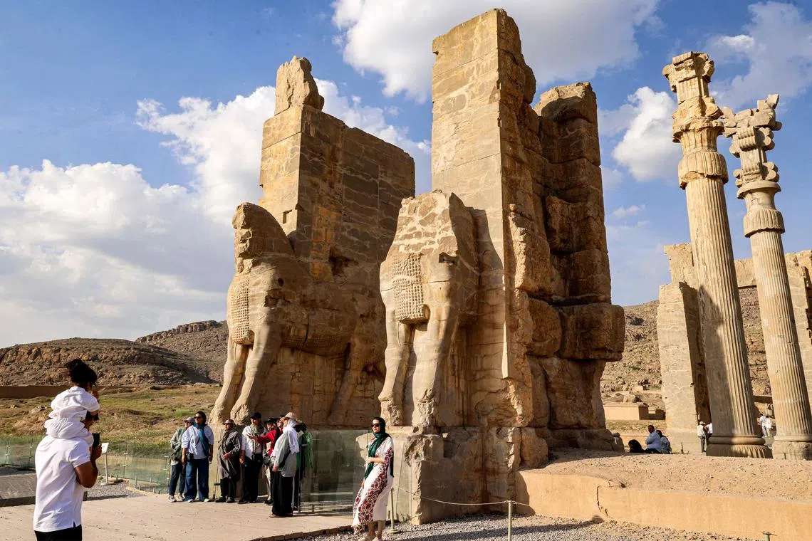 A woman posing for a picture before an ancient gate, while touring through the ruins of ancient Persepolis, which served as the capital of the Achaemenid Persian Empire (550-330 BC), in southern Iran on May 13, 2024. 