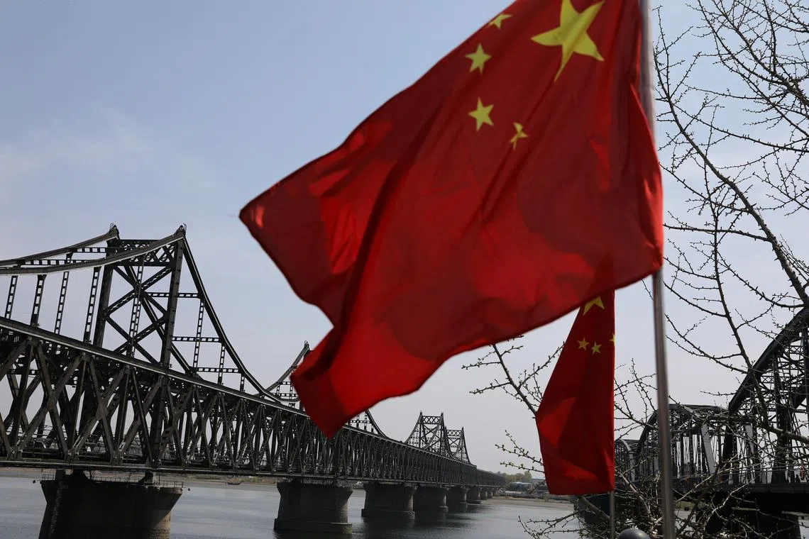 FILE PHOTO: A Chinese national flag flutters near the Friendship Bridge and Broken Bridge over the Yalu River, which separates North Korea's Sinuiju from China, in Dandong, Liaoning province, China April 21, 2021. REUTERS/Tingshu Wang/File photo