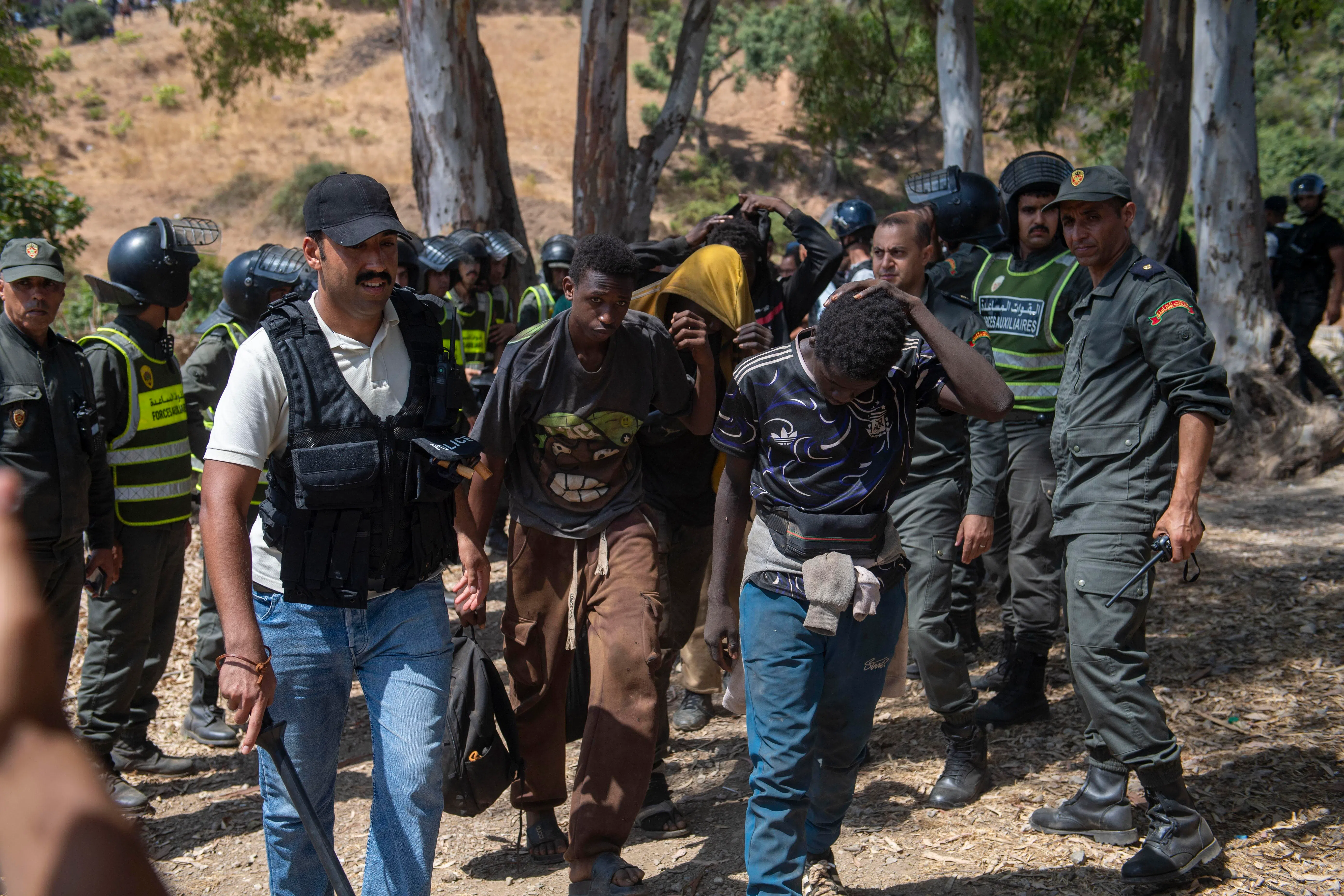 Moroccan security forces arresting migrants trying to enter the north African Spanish enclave of Ceuta on Aug 15.