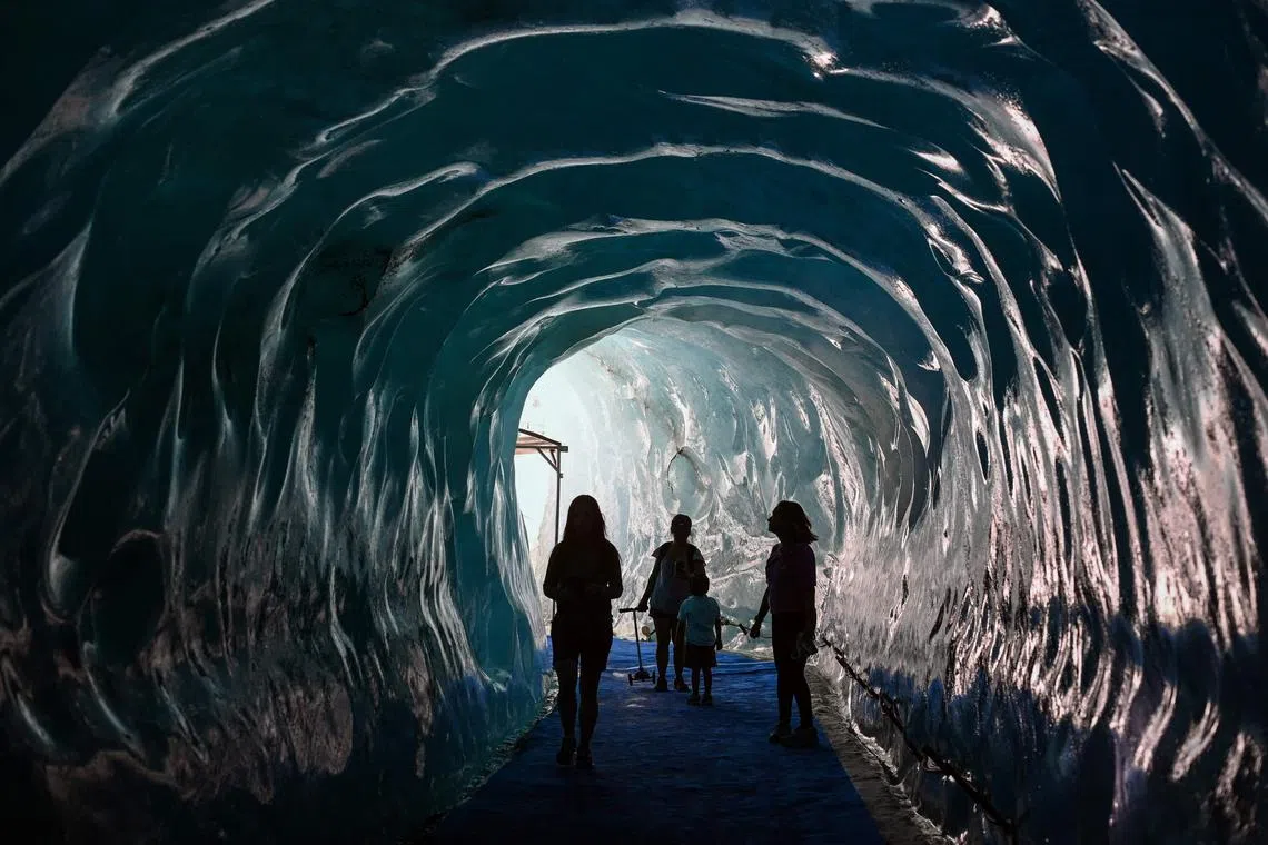 People walking inside the Grotte de Glace (Ice Cave) of the Mer de Glace (Sea of Ice) in Chamonix-Mont-Blanc, in the French Alps on July 11, 2023. 