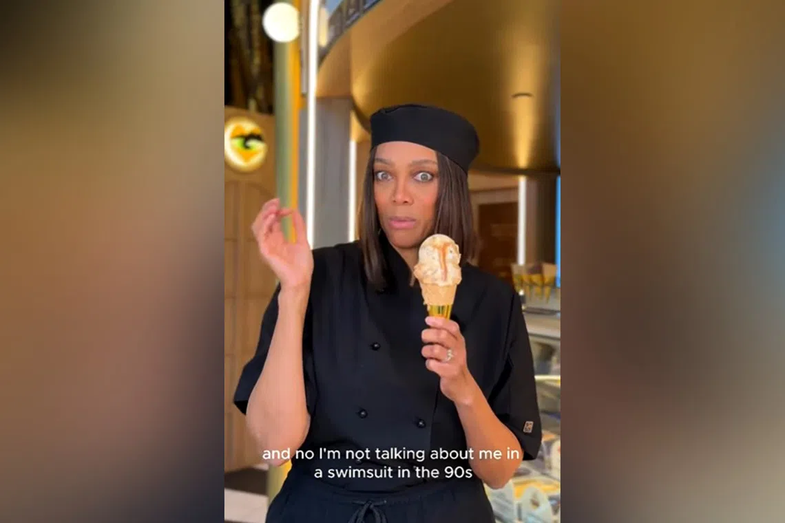 Tyra Banks at her Smize & Dream ice cream shop holding her hot ice cream flavour Hot Mama.