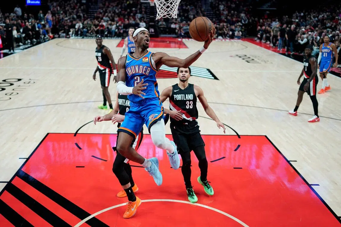 Shai Gilgeous-Alexander of the Oklahoma City Thunder lays up a shot past Deni Avdija of the Portland Trail Blazers during the second half at Moda Center.