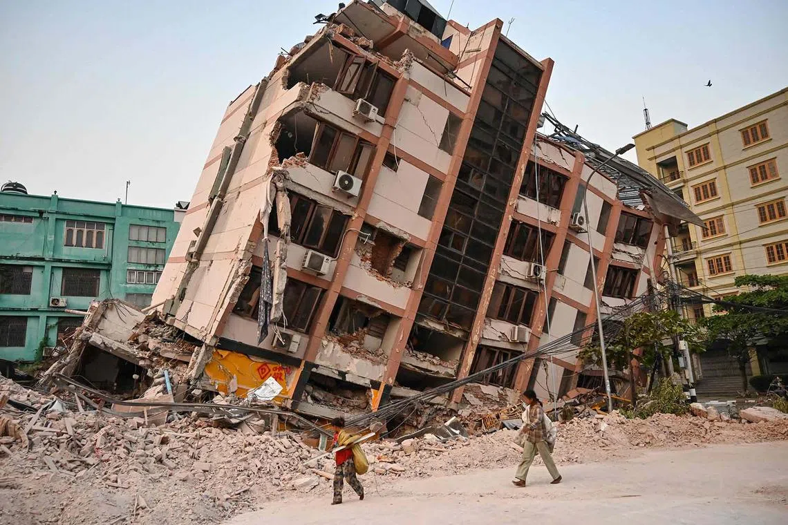 TOPSHOT - Children walk past a collapsed building in Mandalay on April 2, 2025, five days after a major earthquake struck central Myanmar. Days after a shallow 7.7-magnitude earthquake that killed more than 2,000 people, many people in Myanmar are still sleeping outdoors, either unable to return to ruined homes or afraid of further aftershocks. (Photo by AFP)