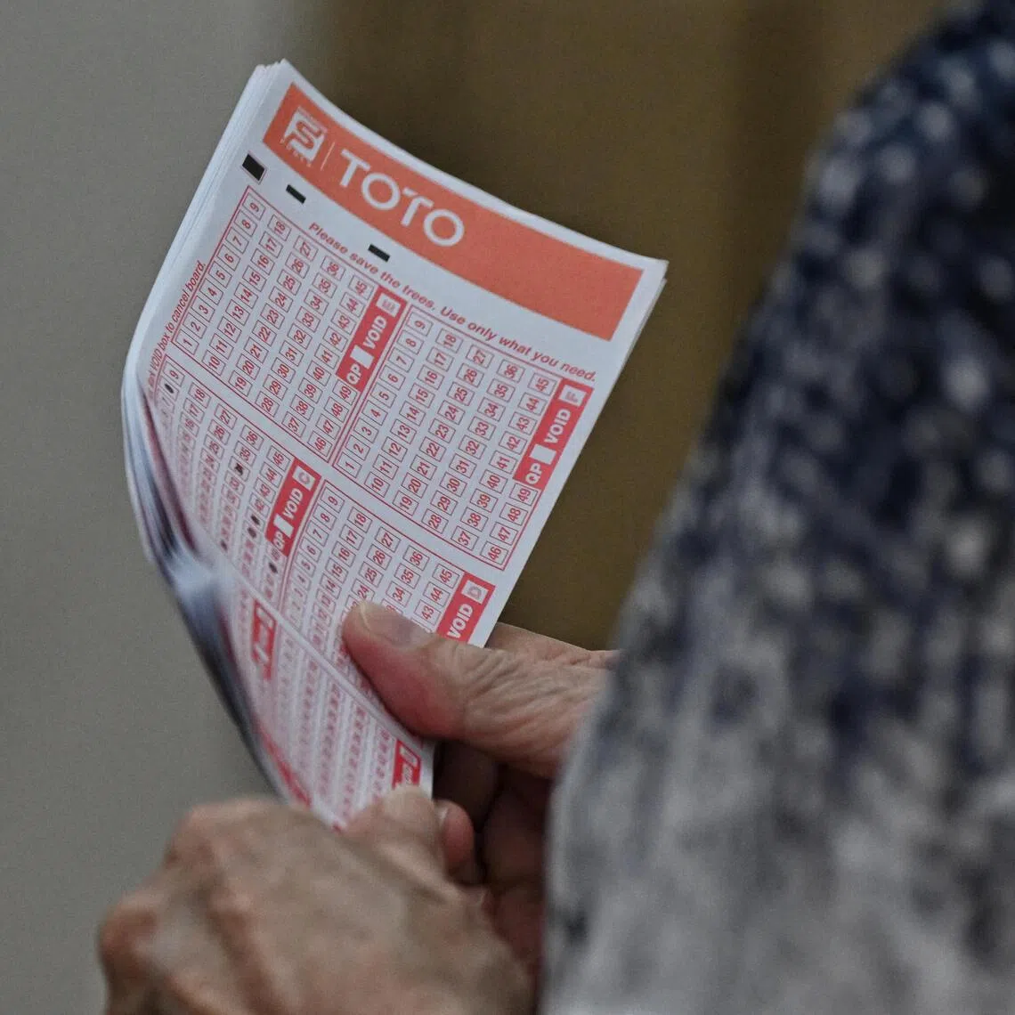 A woman holds her tickets while queueing on the last day to place bets for the Toto Hong Bao Draw, at the Singapore Pool's Outlet at Toa Payoh HDB Centre on Feb 3, 2023.