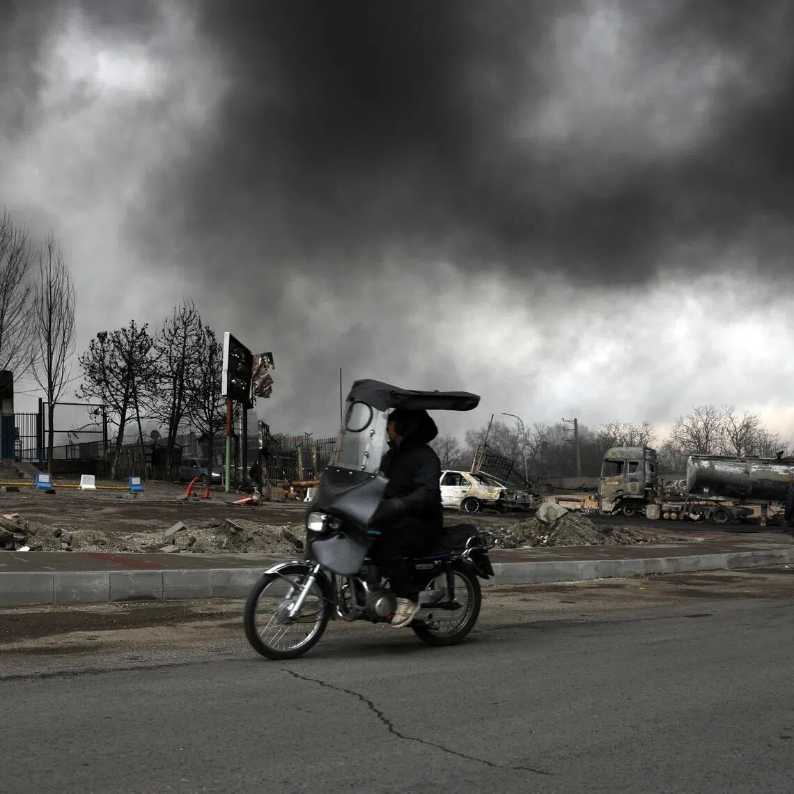 epa12803461 An Iranian man drives past as smoke still rises from Shahran Oil Refinery following last night airstrike in Tehran, Iran, 08 March 2026. A joint Israeli and US military operation continues to target multiple locations across Iran since the early hours of 28 February 2026.  EPA/ABEDIN TAHERKENAREH