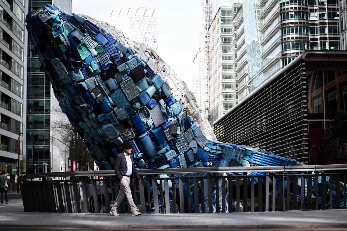 A pedestrian walks past the new art piece of the Canary Wharf’s permanent art collection called Whale On The Wharf, created with plastic waste by US-based artists and architects duo Jason Klimoski and Lesley Chang, in Canary Wharf, in London, on April 18.