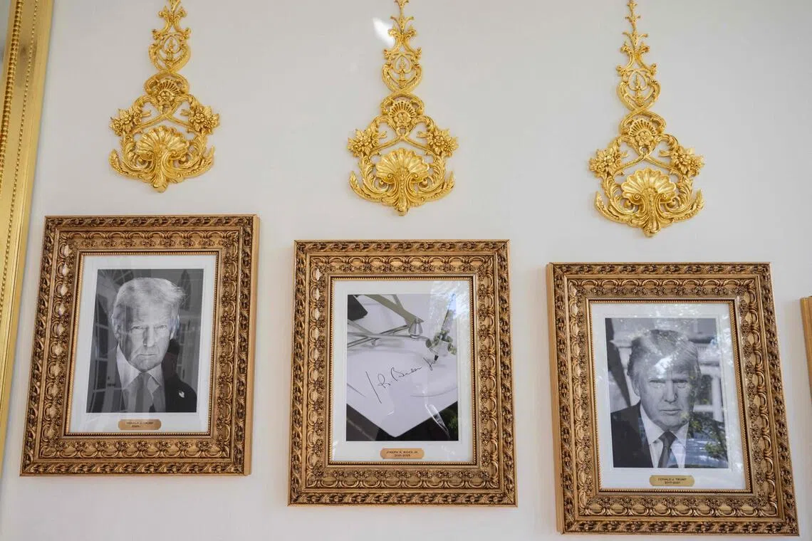 Framed portraits of US President Donald Trump flank a image of former US President Joe Biden's signature and an autopen along "The Presidential Walk of Fame" outside the Oval Office.