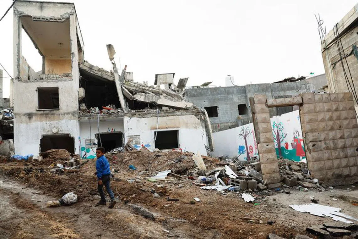 A boy walks near a damaged building after an Israeli raid, at Nour Shams refugee camp in Tulkarm, in the Israeli-occupied West Bank, January 18, 2024. REUTERS/Raneen Sawafta