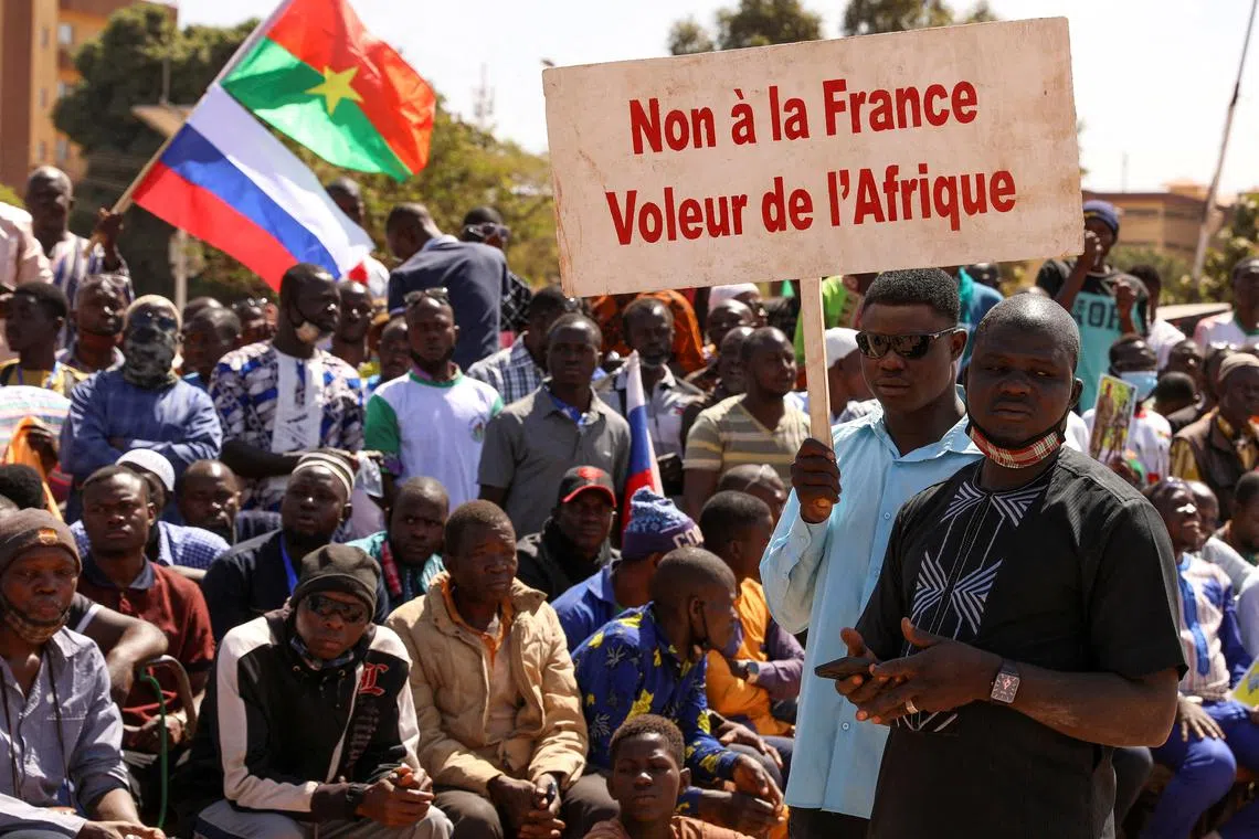 FILE PHOTO: People hold a sign as they gather to show their support to Burkina Faso's new military leader Ibrahim Traore and demand the departure of the French ambassador at the Place de la Nation in Ouagadougou, Burkina Faso January 20, 2023. The sign reads : \"France's army get out from our country\". REUTERS/Vincent Bado/File Photo