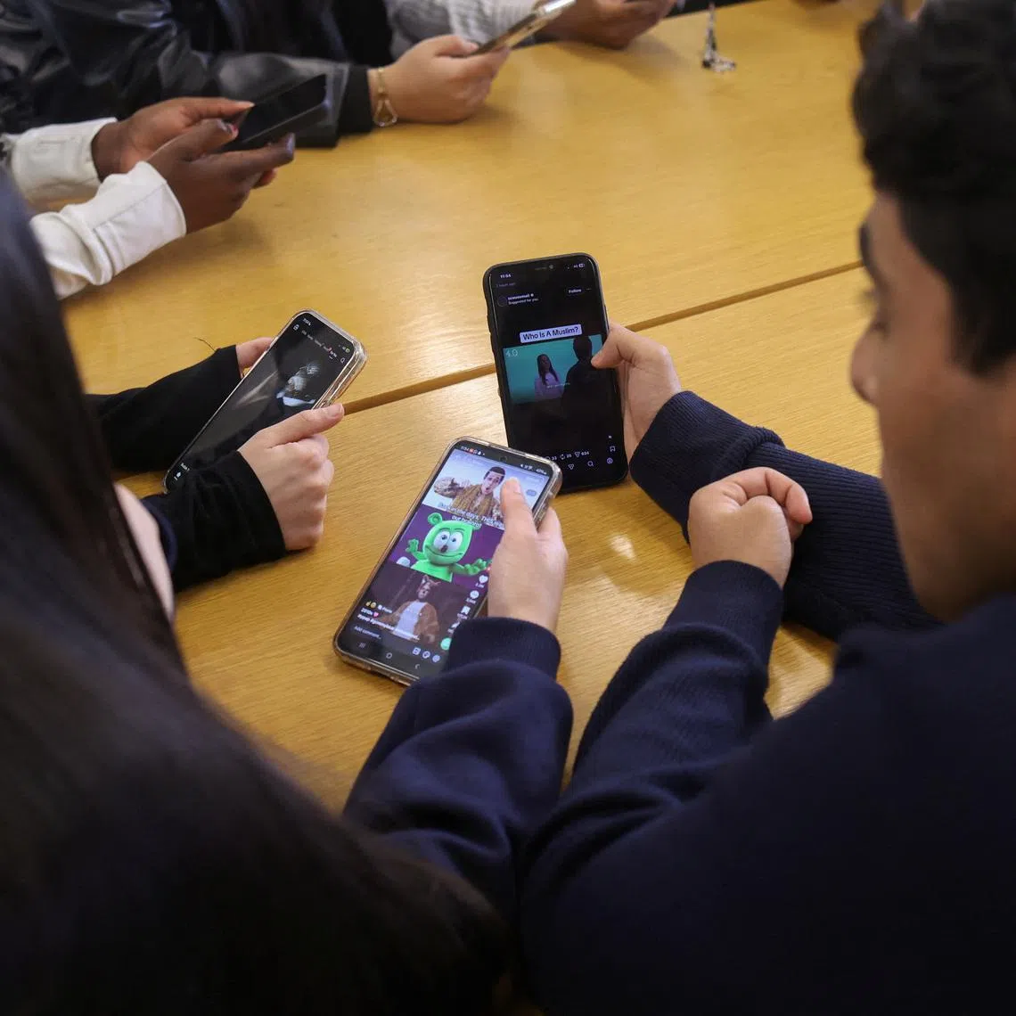 Students from Ricards Lodge and Rutlish High Schools in Wimbledon look at their mobile phones during an interview and discussion with Reuters about their thoughts on a social media ban for under 16s, in London, Britain, February 23, 2026, REUTERS/Katie Collins