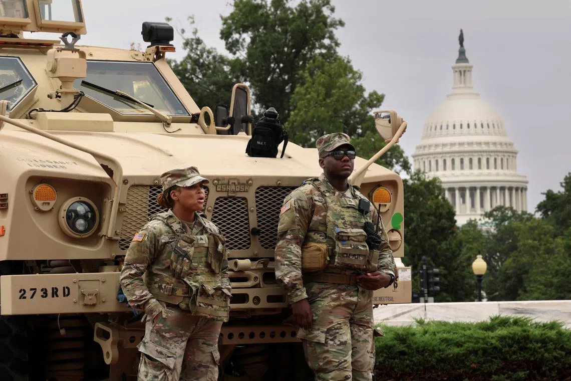 FILE PHOTO: With the dome of the U.S. Capitol in the background, members of the DC National Guard keep watch outside Union Station after U.S. President Donald Trump deployed the National Guard and ordered an increased federal law enforcement presence to assist in crime prevention, in Washington, D.C., August 19, 2025. REUTERS/Kevin Lamarque/File Photo