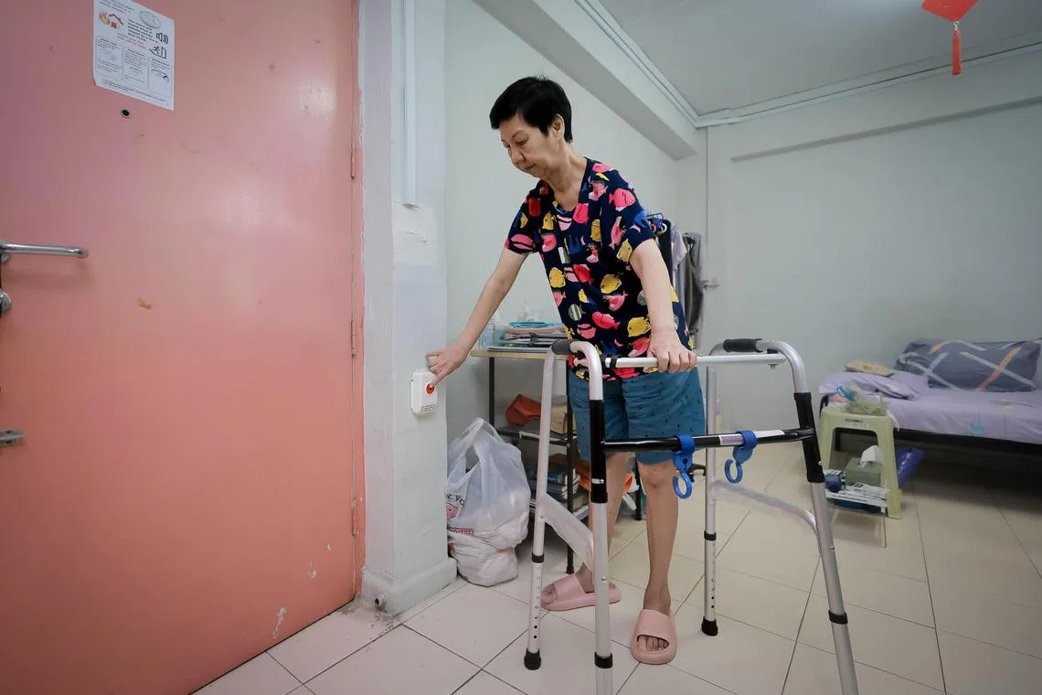 Mdm Khoo Ai Choo, 67, pressing the button on the wireless Alert Alarm System (AAS) located beside the main door in her home in Redhill, Nov 15, 2023.
