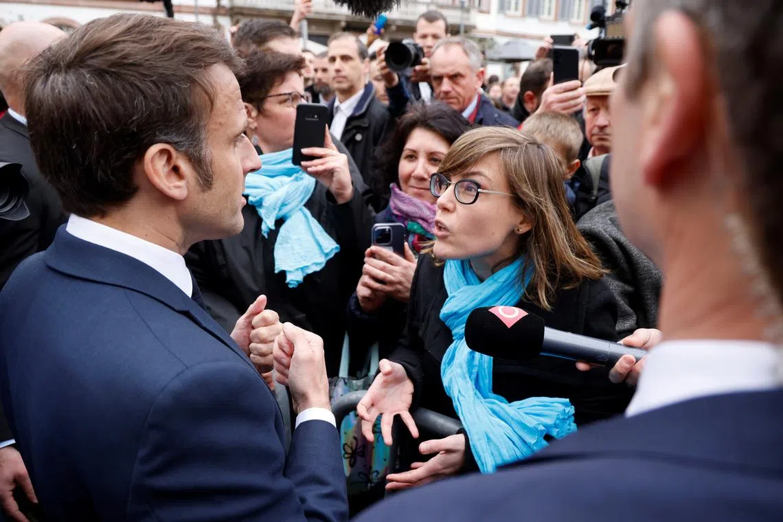 French President Emmanuel Macron (left) talks to a person opposed to the pension reform on April 19, 2023.