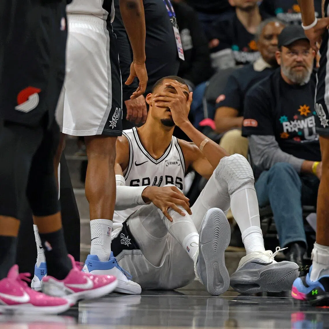 Victor Wembanyama of the San Antonio Spurs holds his head after falling to the court against the Portland Trail Blazers in the first half of Game Two.