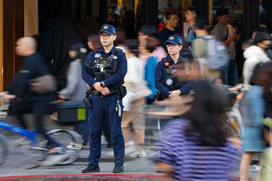 Taiwanese police officers keep watch near the crime scene of a knife attack in Taipei on Dec 20. The suspect was found dead after jumping off a nearby building.