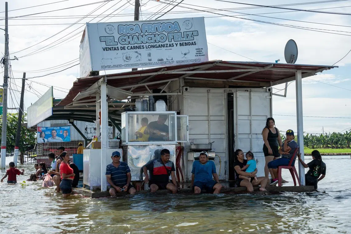 Locals waiting in a flooded area in Babahoyo, Los Rios province, Ecuador on March 4, 2025. Several cities in Ecuador have been seriously affected by the intense rains, which have caused flooding, overflowing rivers and landslides.  