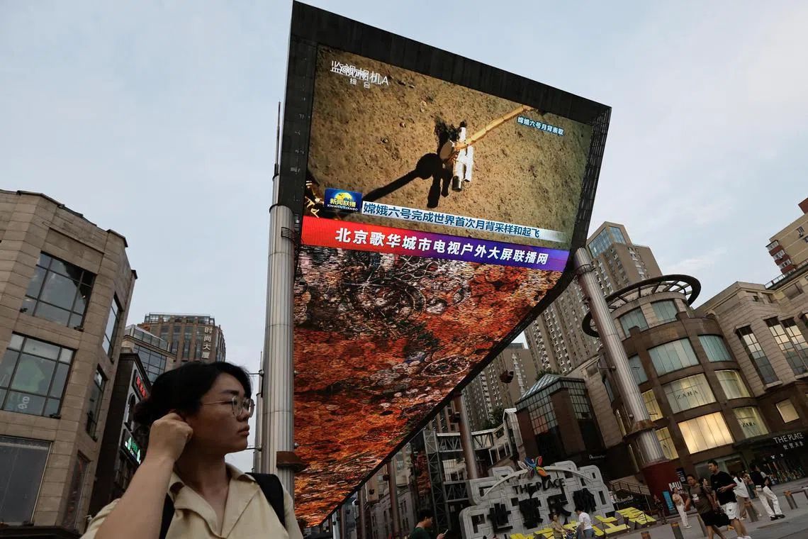A large screen shows news footage of China's Chang'e-6 lunar probe collecting a sample from the far side of the moon, in Beijing, on June 4. 