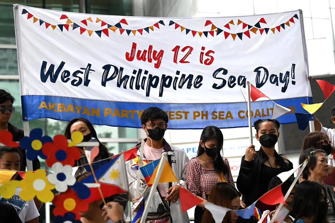 Protesters wave flags in front of the Chinese Consulate in Manila to press a ruling voiding China's territorial claims.
