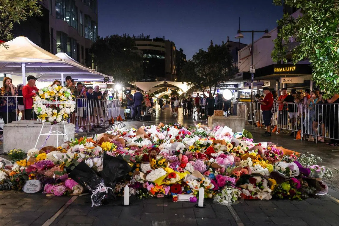 Members of the public look at flowers placed outside the Westfield Bondi Junction shopping mall in Sydney on April 14.