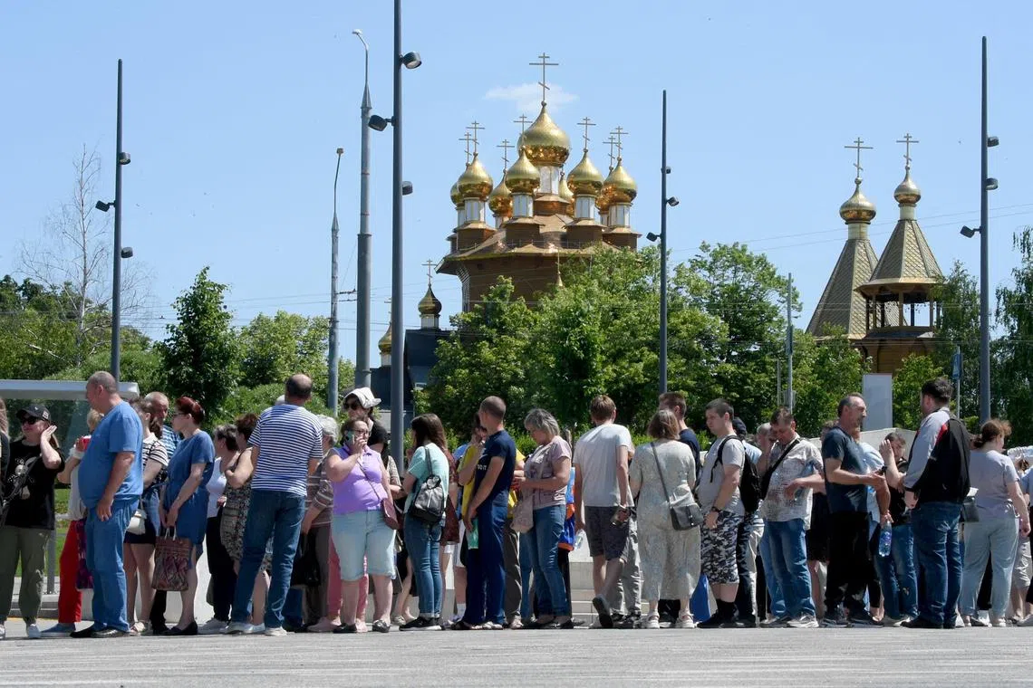 Residents, including those evacuated from the town of Shebekino, queue outside a temporary shelter in Belgorod.