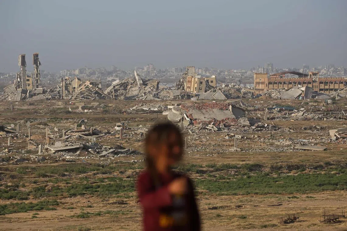 A Palestinian girl stands against the backdrop of buildings destroyed amid the ongoing conflict in Deir al-Balah, central Gaza Strip on May 13, 2026.