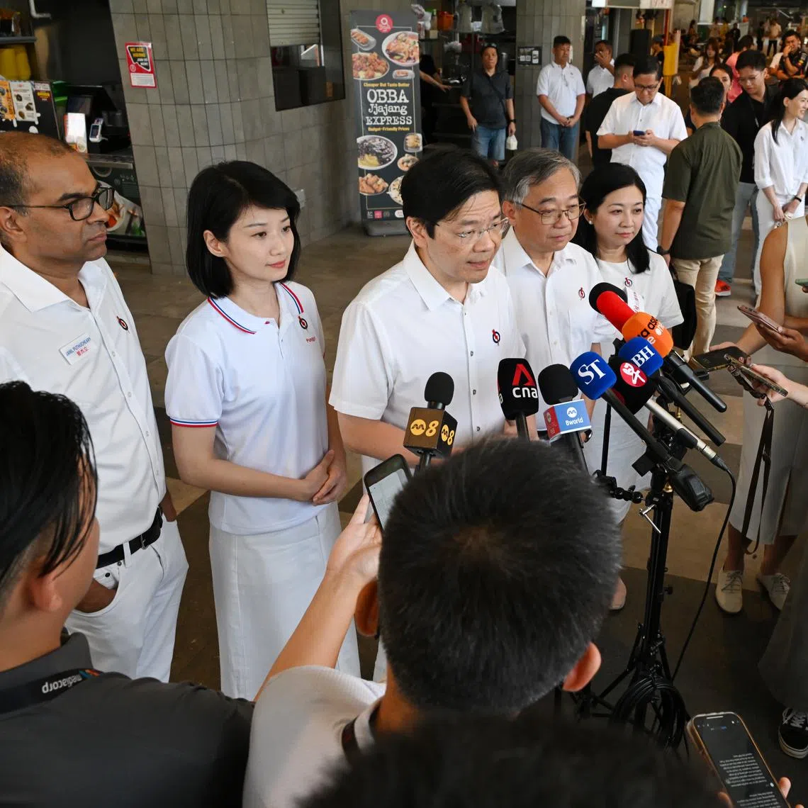 PM Lawrence Wong (centre), flanked by the PAP's Punggol GRC candidates (from left) Janil Puthucheary, Sun Xueling, Gan Kim Yong and Yeo Wan Ling, speaking to the media on the sidelines of a walkabout at the One Punggol Hawker Centre on April 29.