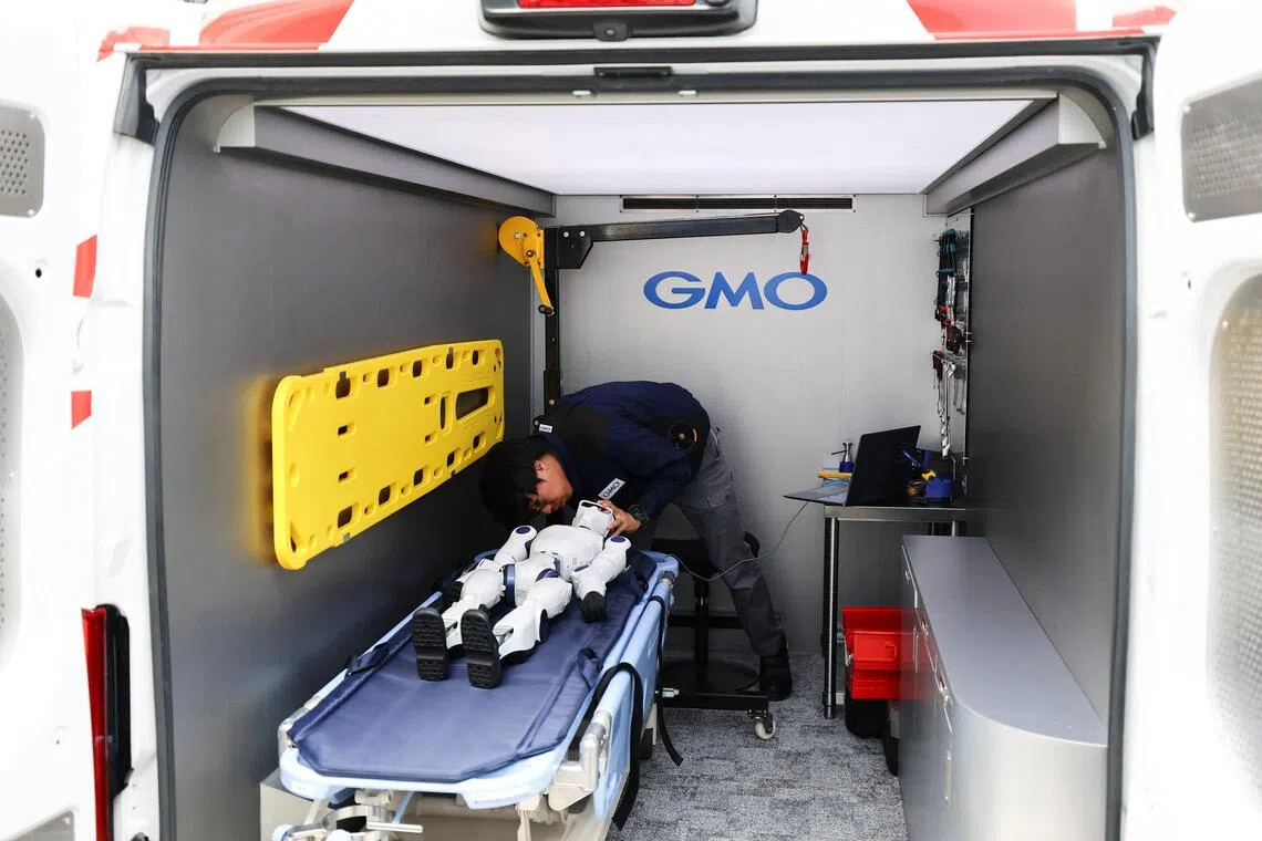A humanoid robot lies down inside a maintenance vehicle dedicated to humanoid robots called a "GMO Humanoid Ambulance", a specialized vehicle that rushes to the scene of malfunctions or issues with humanoid robots to perform on-site diagnostics and repairs, or to provide replacement equipment, during an uveiling event to announce new services by GMO AI & Robotics Corporation (GMO AIR) in Tokyo, Japan, September 8, 2026.  REUTERS/Issei Kato