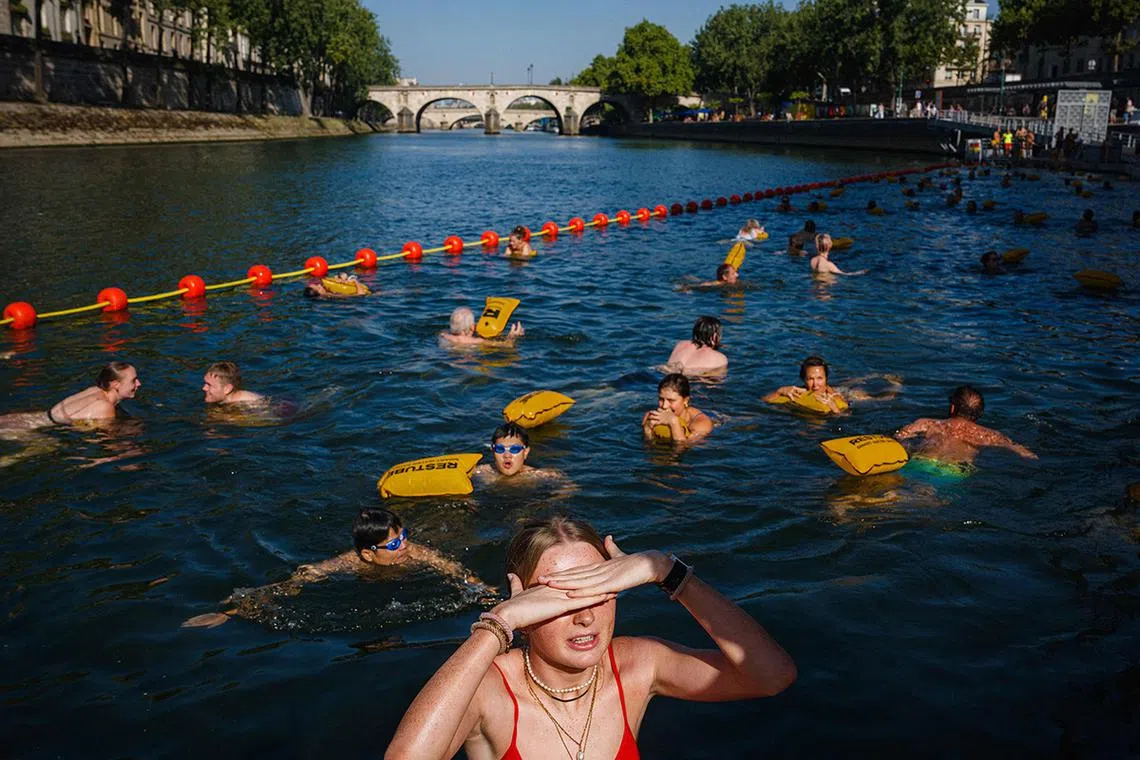 TOPSHOT - People swim at the Bras Marie safe bathing site on the river Seine in Paris on August 12, 2025. France continues to suffocate with 14 departments in the southwest and southeast on red alert for heatwave on August 12, 2025, an exceptional heat wave, even for the month of August, which is prompting authorities to increase precautionary measures. (Photo by Dimitar DILKOFF / AFP)