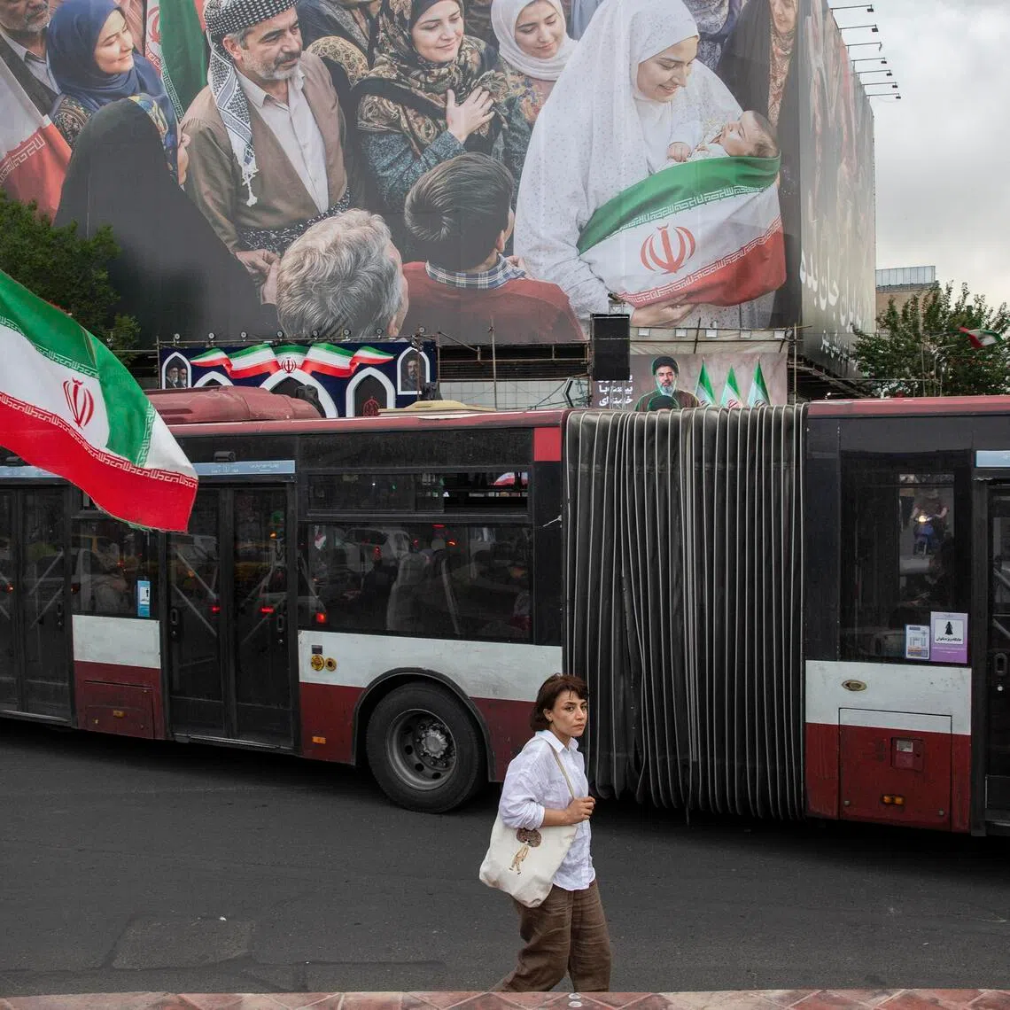 A woman waves an Iranian flag near a new billboard in Enghelab Square in Tehran, Iran, on May 24.