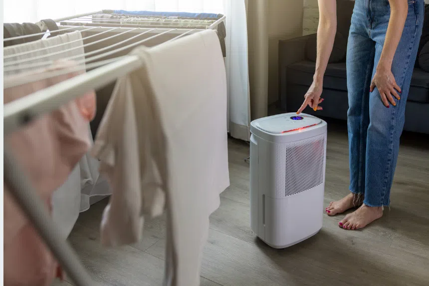 Best dehumidifiers in Singapore: Woman turning on a dehumidifier to dry clothes indoors