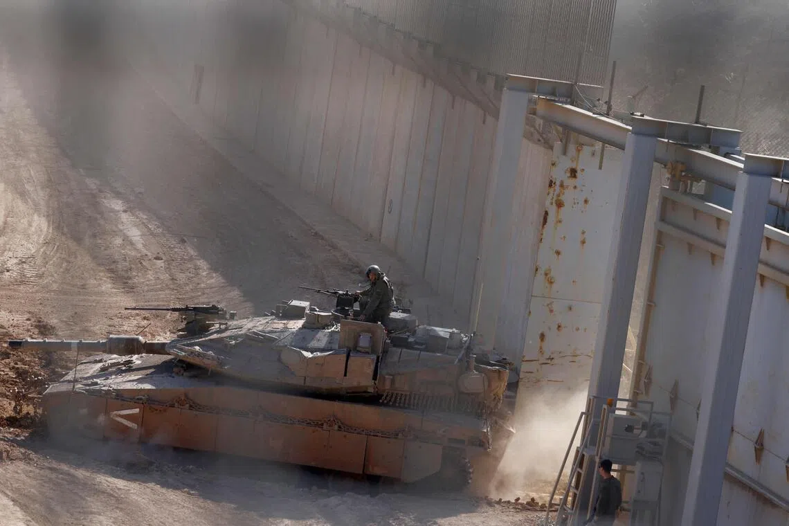 An Israeli military tank patrols close to a concrete wall along the border fence separating northern Israel from southern Lebanon.