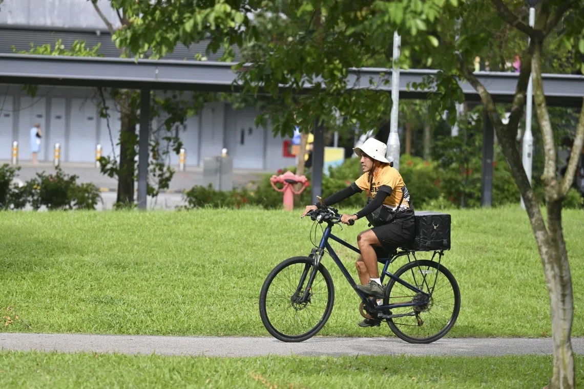 Delivery rider cycles with a hat to cope with heat