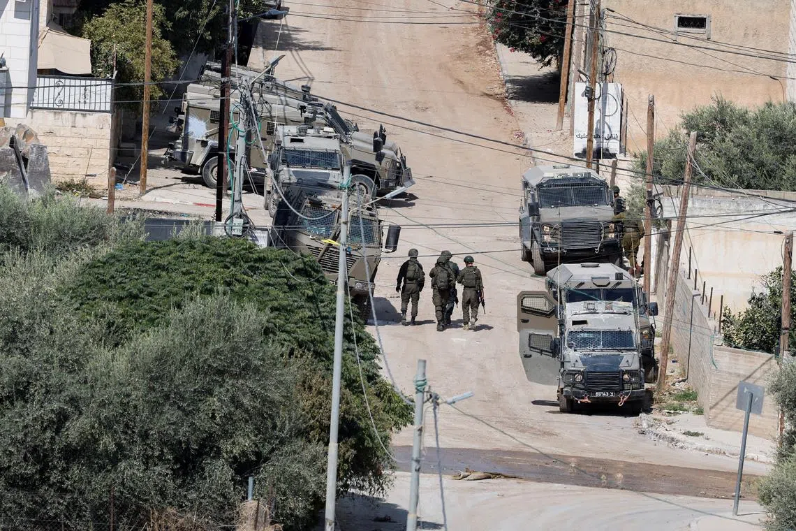FILE PHOTO: Israeli security forces walk next to armoured vehicles during an Israeli raid in Jenin during an Israeli raid, in Jenin, in the Israeli-occupied West Bank, September 3, 2024. REUTERS/Raneen Sawafta/File Photo
