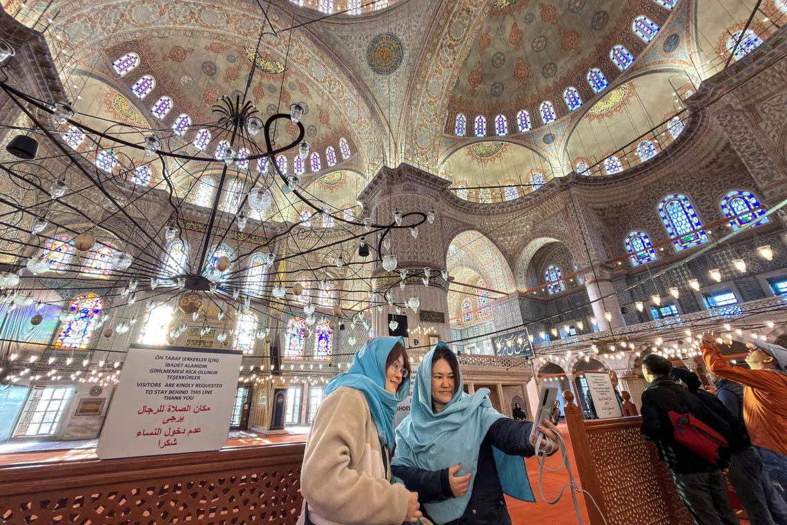 Japanese tourists pose for a selfie as they visit Ottoman-era Sultanahmet Mosque, known as the Blue Mosque, which Pope Leo XIV is expected to visit later this week, in Istanbul, Turkey, November 25, 2025. REUTERS/Murad Sezer