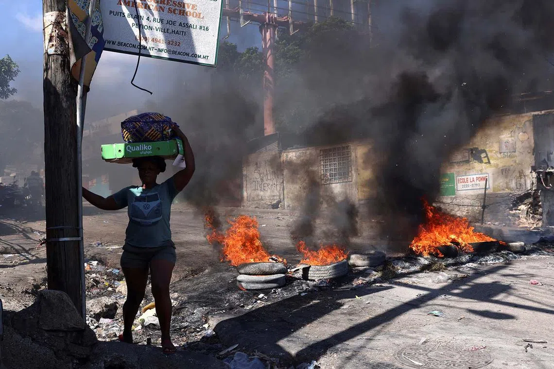 A woman walks past a burning barricade set during a protest against insecurity, in the Petion-Ville neighborhood of Port-au-Prince, Haiti April 2, 2025. REUTERS/Ralph Tedy Erol TPX IMAGES OF THE DAY