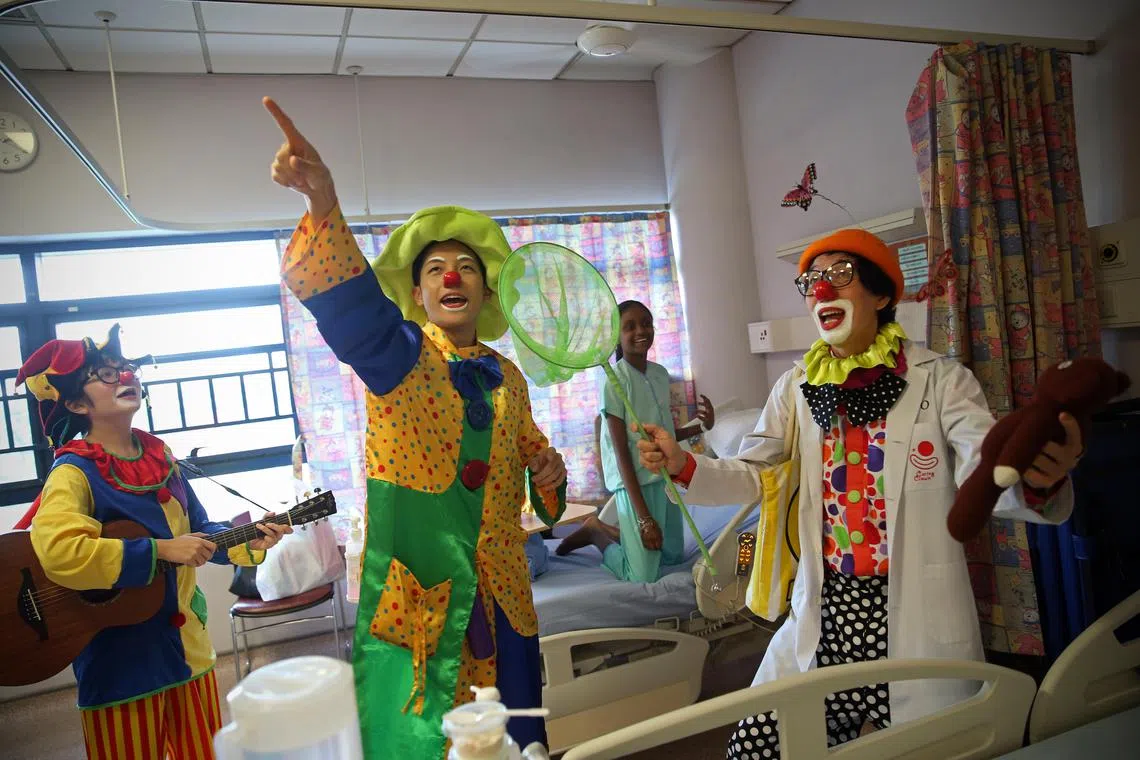 11-year-old Vinitha Suresh (second from right) reacts as members of the Caring Clown Unit (from left) Shootie, Rong Er and Rojo, comically search for butterflies in the ward. It is part of Rojo's signature act to engage his audience - he endlessly hunts for butterflies that he cannot see on top of his hat. Formed in 2004, the Caring Clown Unit (CCU) Singapore is a not-for-profit outfit, that started with the expressed objective of making a positive difference in the lives of hospitalised patients, their families and caregivers by spreading warmth and cheer through humorous ward entertainment. The volunteers visit the paediatric wards of KK Women’s and Children’s Hospital every last Saturday of the month to sculpt balloons, perform magic tricks, and basically be silly, to try and make a child smile.