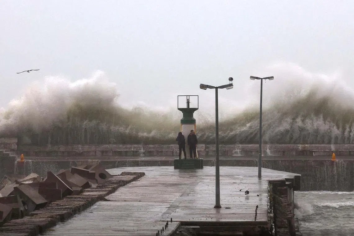 People look at large waves crashing against the Kalk Bay harbour wall during severe weather conditions in Cape Town, South Africa, Sept 24.