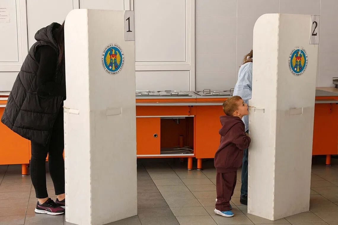 A child standing next to a voting booth at a polling station during Moldova's parliamentary elections in Chisinau, Moldova, Sept 28, 2025. 