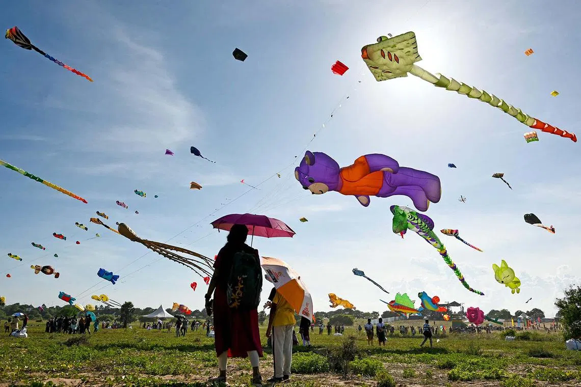 TOPSHOT - People look at animated kites soaring over the sky on the third day of the Tamil Nadu International Kite Festival on the outskirts of Chennai on August 17, 2024. (Photo by R. Satish BABU / AFP)