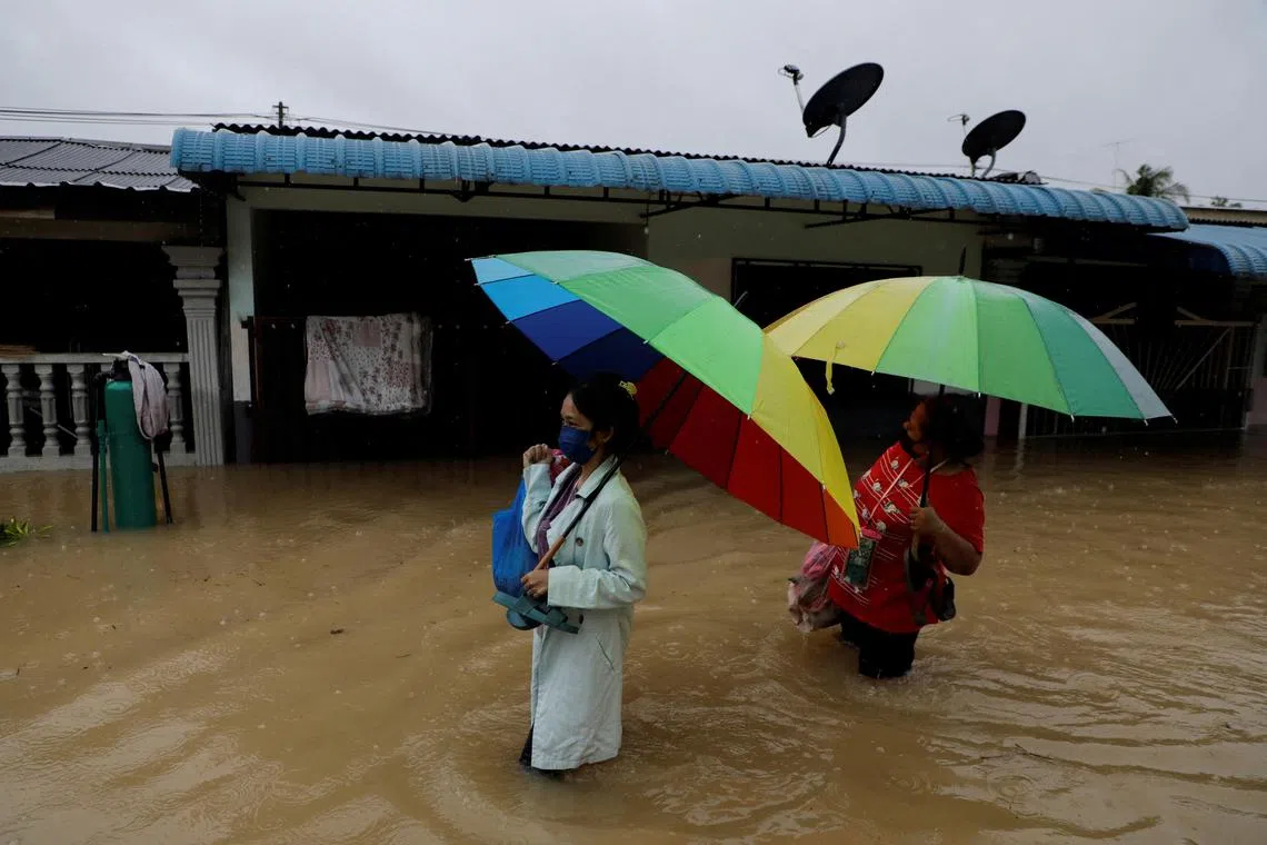 People wade through a flooded residential area at Yong Peng, Johor.